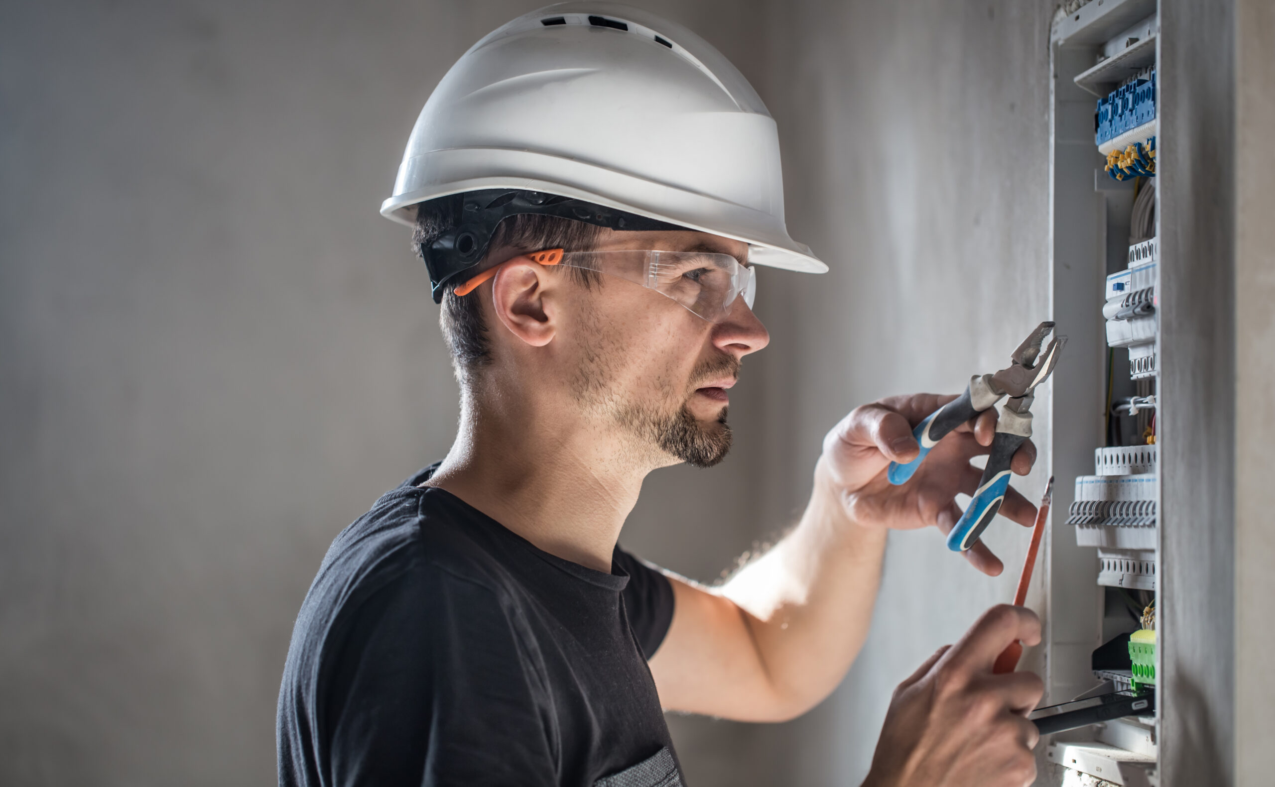 man, an electrical technician working in a switchboard with fuses. installation and connection of electrical equipment.